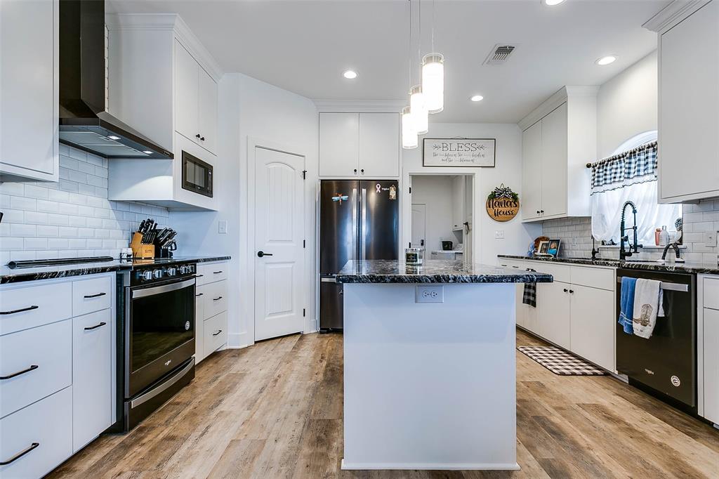 12487 County Road 4102 Hermleigh, TX 79526 - Photo 6 of 40 a kitchen with stainless steel appliances granite countertop a refrigerator a sink dishwasher a stove and white countertops with wooden floor