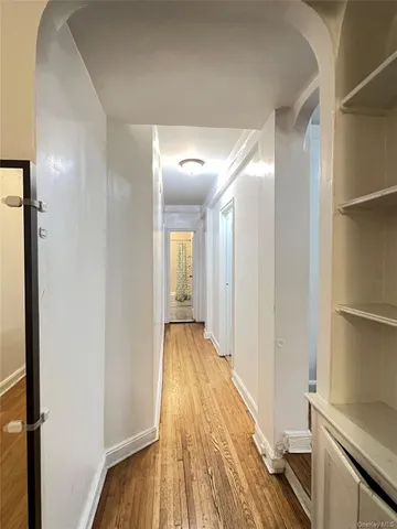 a view of a hallway with wooden floor and bathroom