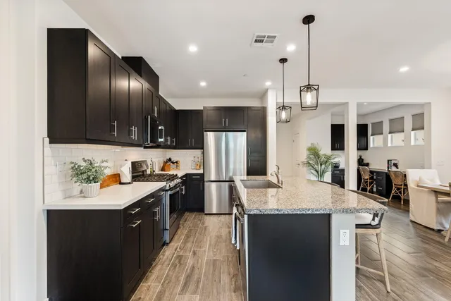 a kitchen with granite countertop stainless steel appliances a sink stove and refrigerator
