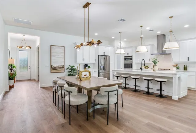 a kitchen with stainless steel appliances a table chairs refrigerator and cabinets