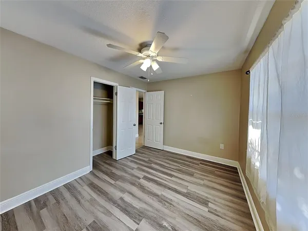 a view of an empty room and window and chandelier fan