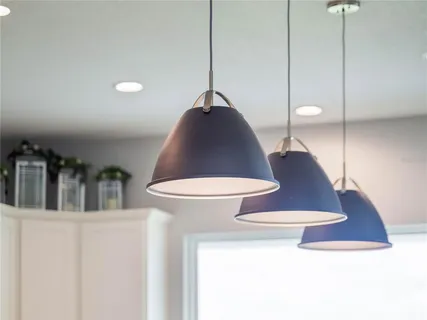 a kitchen with stainless steel appliances granite countertop a sink a stove a refrigerator cabinets and chairs