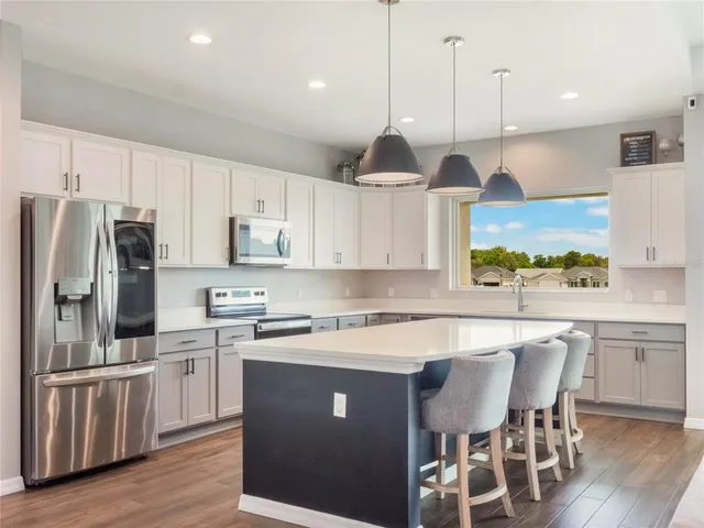 a large kitchen with stainless steel appliances lots of counter space dining table and a large window