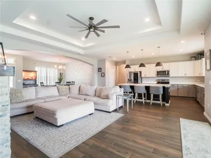 a living room with couches and kitchen view with wooden floor