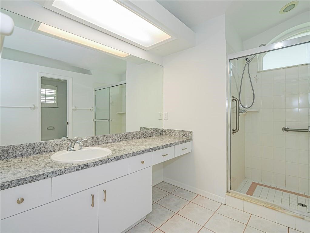 6445 55th Square Vero Beach, FL 32967 - Photo 14 of 36 a bathroom with a granite countertop sink a mirror and a shower