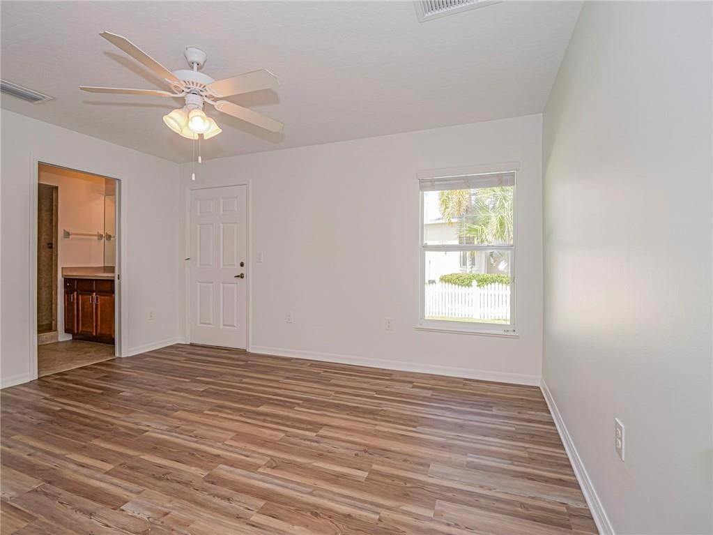 6445 55th Square Vero Beach, FL 32967 - Photo 24 of 36 an empty room with wooden floor chandelier fan and windows