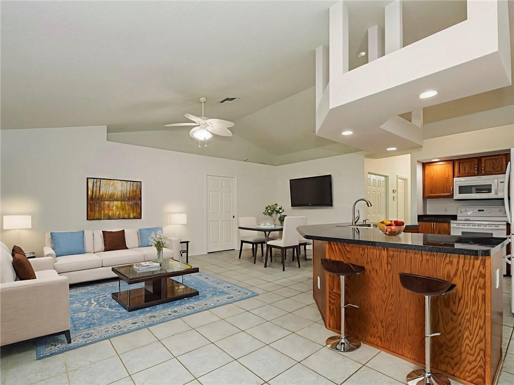 6445 55th Square Vero Beach, FL 32967 - Photo 8 of 36 a living room with furniture a flat screen tv and kitchen view