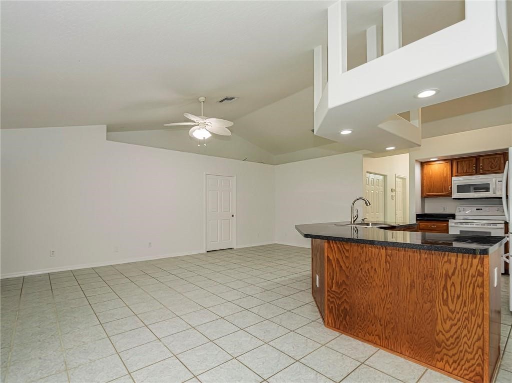 6445 55th Square Vero Beach, FL 32967 - Photo 9 of 36 a kitchen with stainless steel appliances granite countertop a sink and a stove