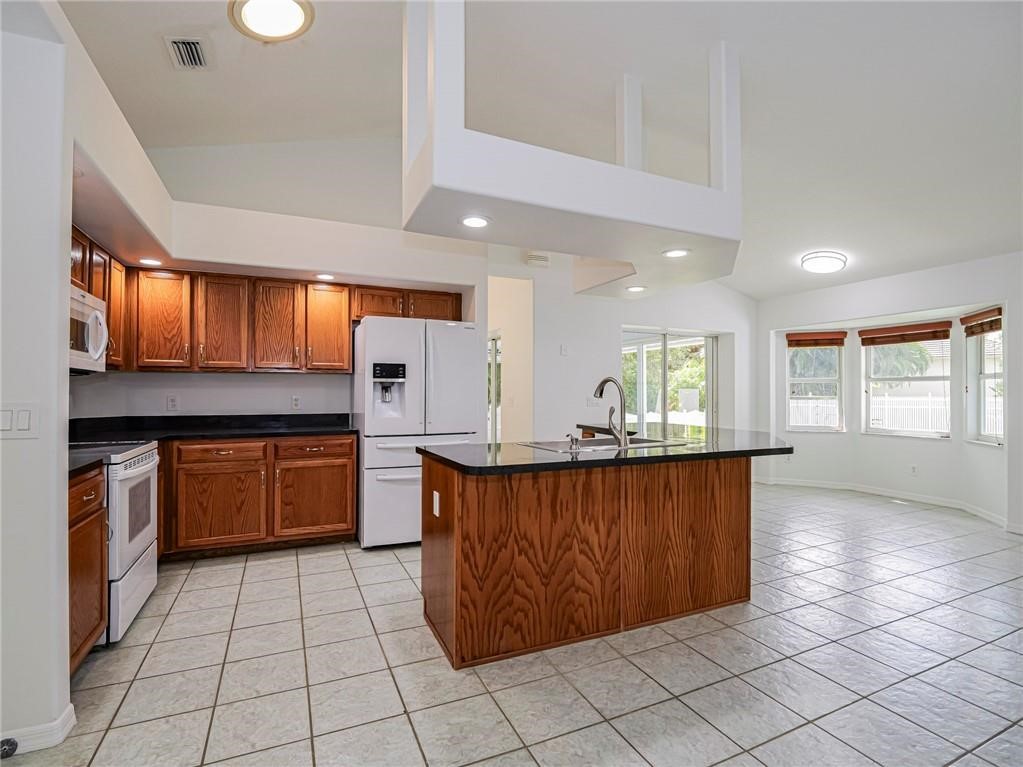 6445 55th Square Vero Beach, FL 32967 - Photo 9 of 36 a kitchen with stainless steel appliances granite countertop a stove a sink and a microwave