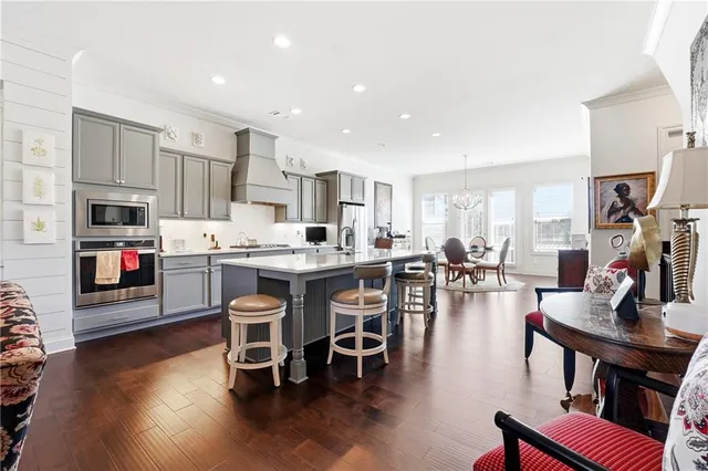 a kitchen with stainless steel appliances kitchen island granite countertop a table chairs and a refrigerator