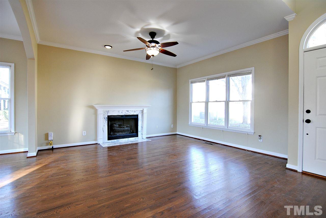 2216 Dahlgreen Road Raleigh, NC 27615 - Photo 4 of 22 an empty room with wooden floor fireplace and windows
