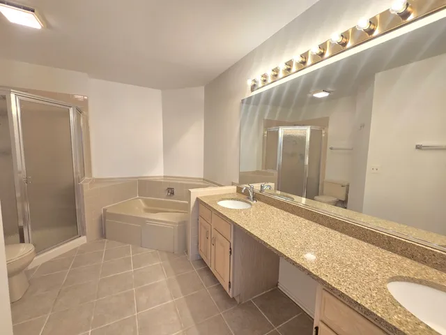 a spacious bathroom with a granite countertop double vanity sink a mirror and a bathtub