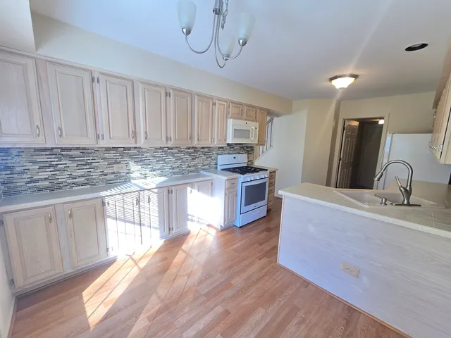 a kitchen with stainless steel appliances granite countertop a sink a stove a refrigerator cabinets and wooden floor