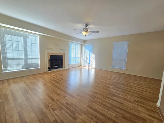 an empty room with wooden floor fireplace and windows