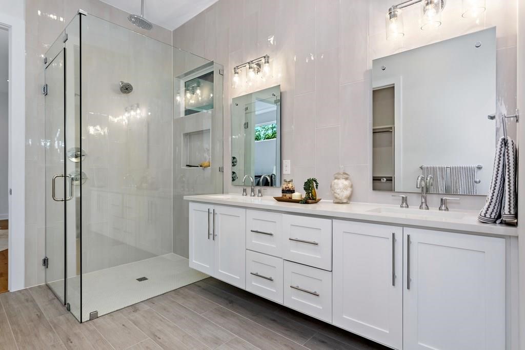 1719 Bunche Road Austin, TX 78721 - Photo 8 of 22 A well-appointed bathroom offers a dual vanity, a frameless glass shower, and rich tile flooring.