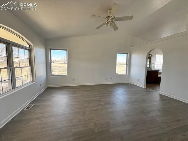 a view of an empty room with a window and wooden floor