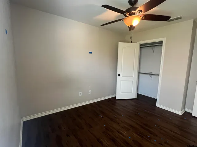 an empty room with wooden floor a ceiling fan and closet