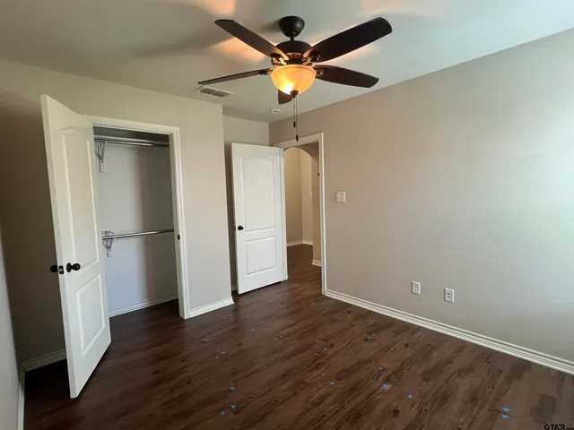 an empty room with wooden floor and a ceiling fan