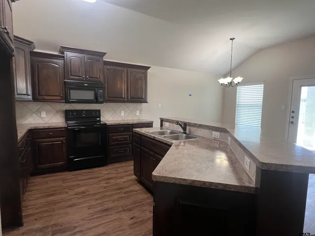 a kitchen with a sink a counter space appliances and a window