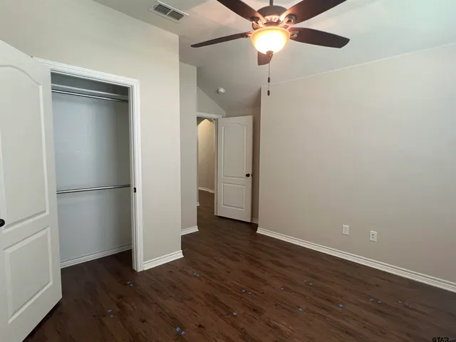 an empty room with wooden floor and a ceiling fan
