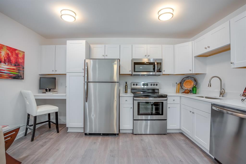 1809 Bennett Avenue, Unit 117 Dallas, TX 75206 - Photo 3 of 5 Kitchen with appliances with stainless steel finishes, white cabinetry, sink, and light hardwood / wood-style floors