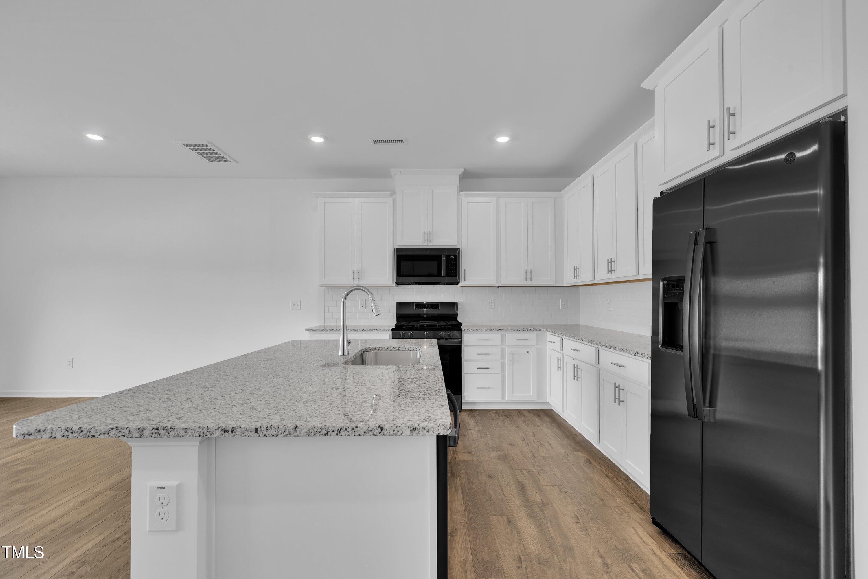 281 Hank Way Angier, NC 27501 - Photo 9 of 39 a kitchen with granite countertop a refrigerator a sink a stove a microwave and island