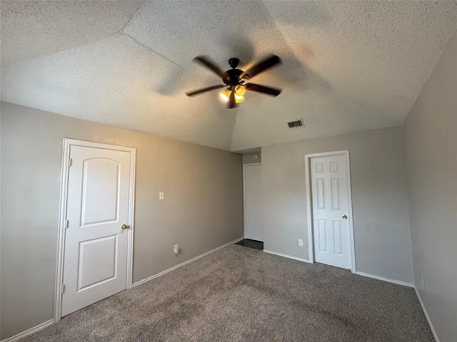 an empty room with closet and a ceiling fan