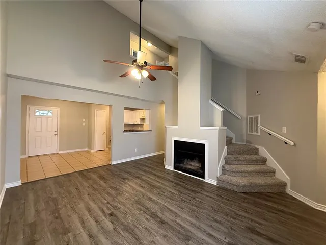 a view of an empty room with wooden floor fireplace and a window