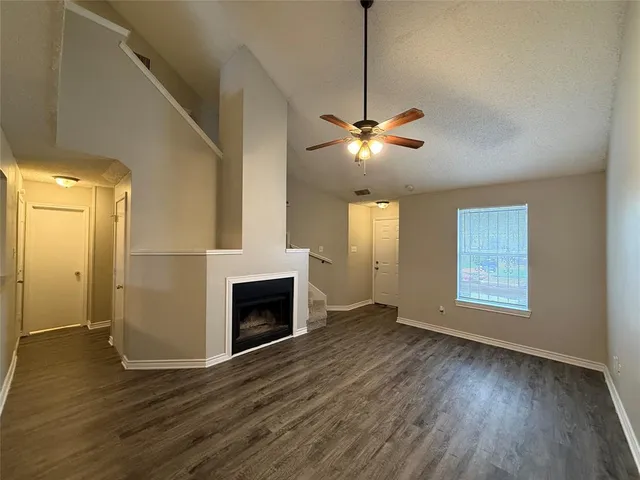 a view of an empty room with wooden floor fireplace and a window