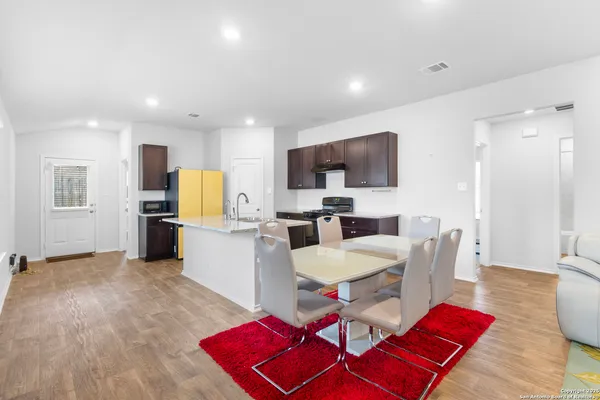 a living room with furniture a kitchen view and a wooden floor