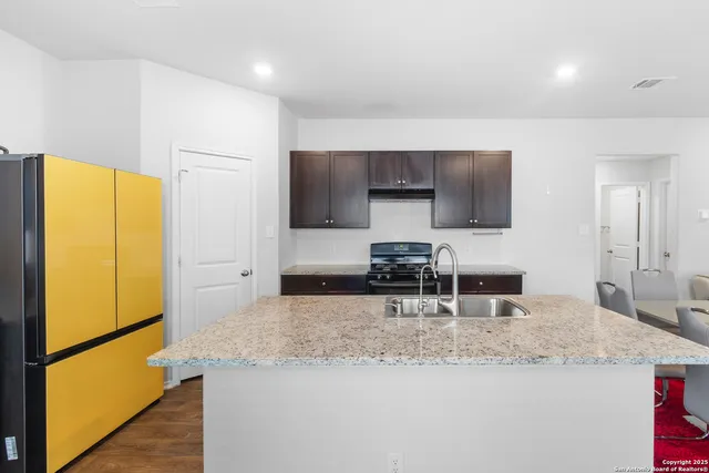 a kitchen with granite countertop a sink a stove and a refrigerator