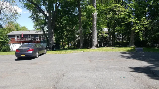 a car parked in front of a house with yard and trees