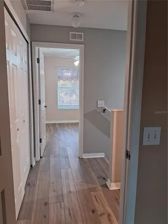 a view of an empty room with wooden floor and a ceiling fan