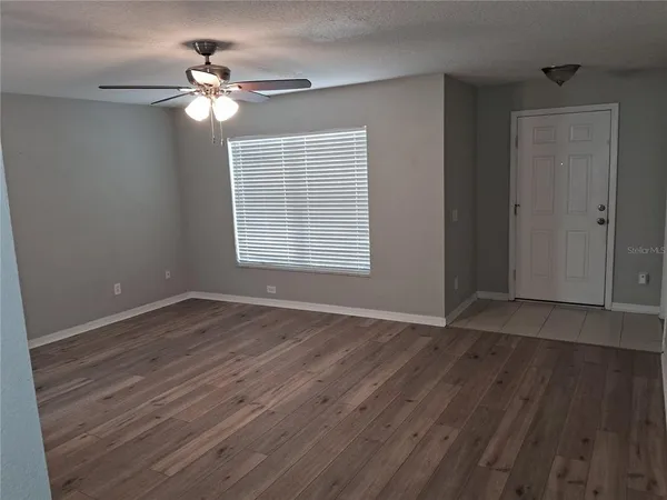 a view of an empty room with wooden floor and a window