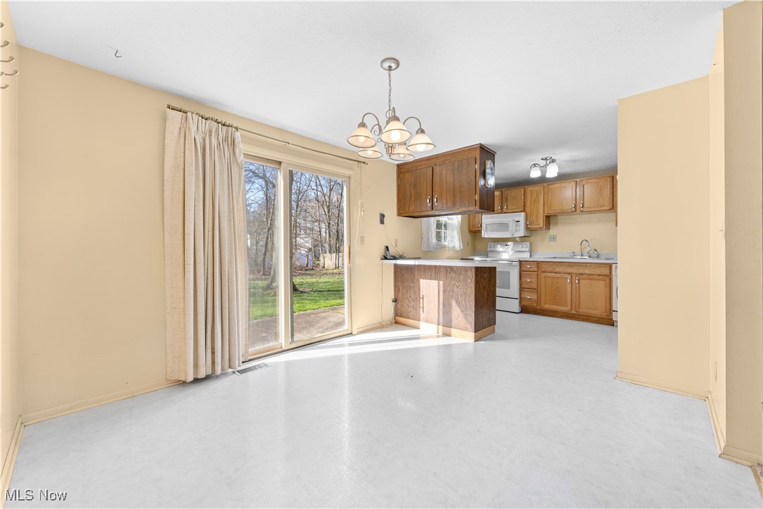 4301 Baird Road Stow, OH 44224 - Photo 10 of 50 Kitchen featuring brown cabinets, visible vents, a sink, white appliances, and a chandelier