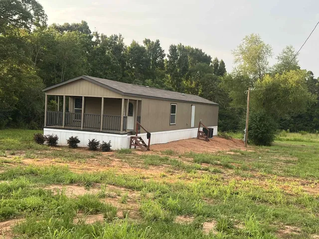a view of a house with a yard and large tree
