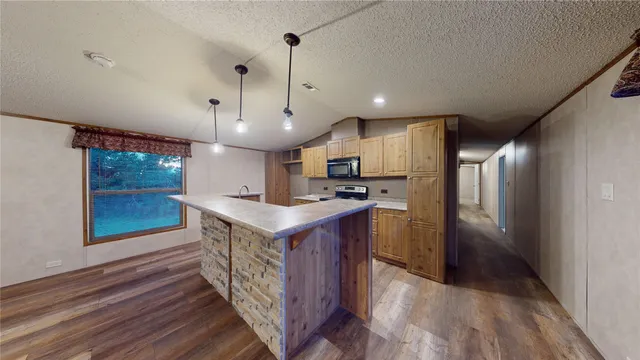 a kitchen with kitchen island a wooden floor and a refrigerator