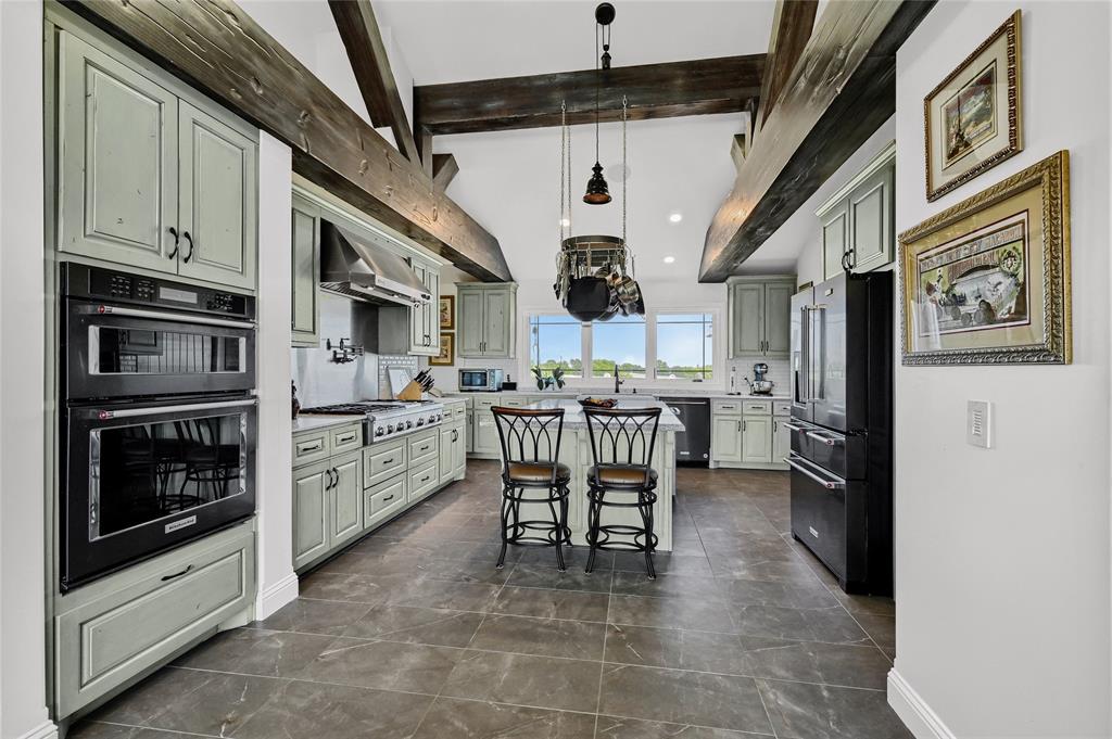 5555 County Road 179 Celina, TX 75009 - Photo 14 of 40 Kitchen featuring a kitchen breakfast bar, a kitchen island, black appliances, hanging light fixtures, and tasteful backsplash