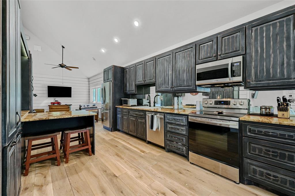5555 County Road 179 Celina, TX 75009 - Photo 37 of 40 Kitchen with light stone countertops, stainless steel appliances, light wood finished floors, high vaulted ceiling, and ceiling fan