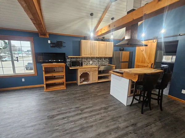 a kitchen with stainless steel appliances wooden floors and white walls