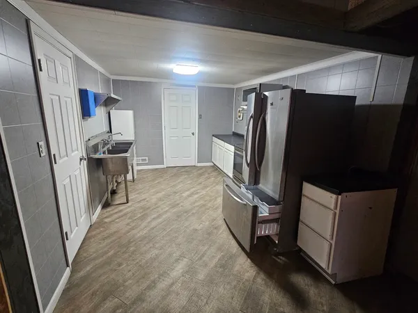 a view of a refrigerator in kitchen and an empty room