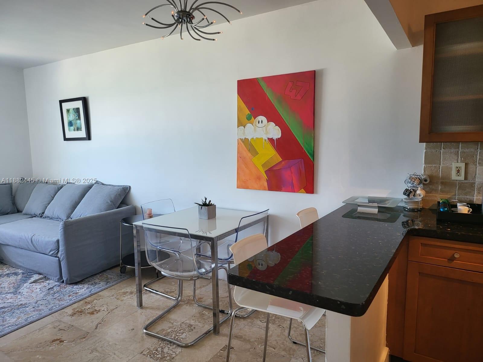 100 Lincoln Road, Unit 1238 Miami Beach, FL 33139 - Photo 23 of 31 a kitchen with stainless steel appliances kitchen island granite countertop a table and a chair
