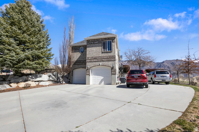 684 North Summit Way Alpine, UT 84004 - Photo 5 of 58 View of side of property with concrete driveway, brick siding, an attached garage, and a mountain view