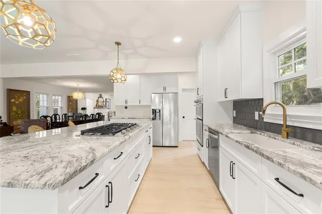 a large kitchen with granite countertop a sink stove refrigerator and cabinets