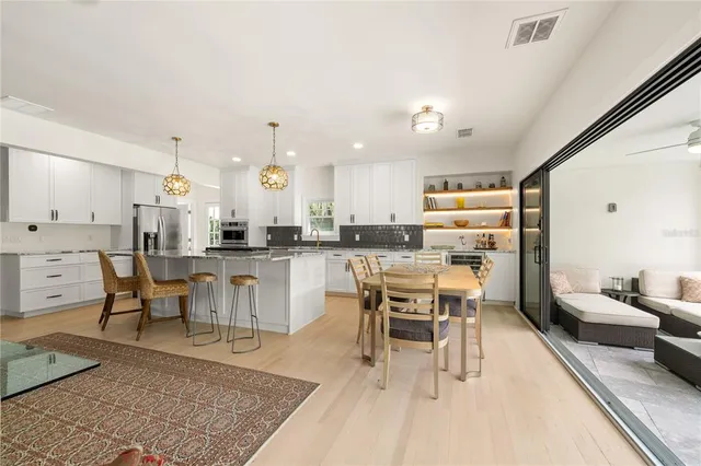 a kitchen with stainless steel appliances kitchen island granite countertop a stove a sink a dining table and chairs with wooden floor