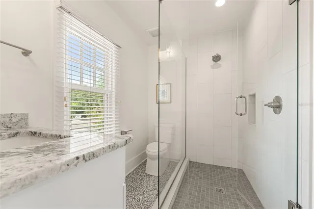 a bathroom with a granite countertop sink a mirror and shower