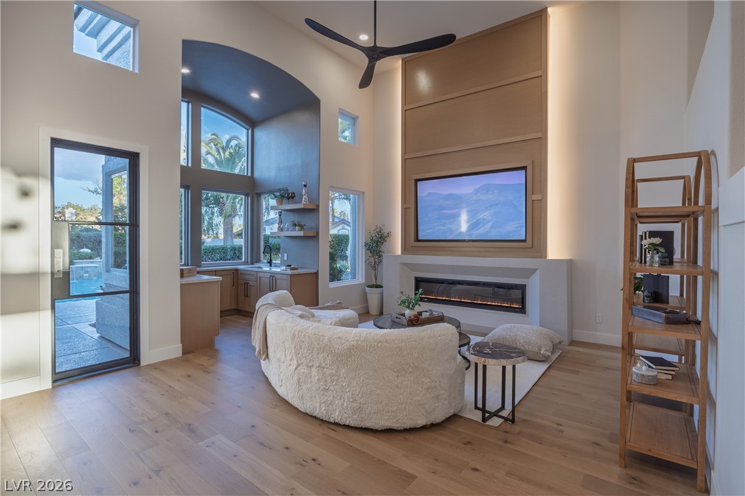 8800 Lusso Las Vegas, NV 89134 - Photo 25 of 85 Living area with a high ceiling, a glass covered fireplace, light wood finished floors, a ceiling fan, and healthy amount of natural light
