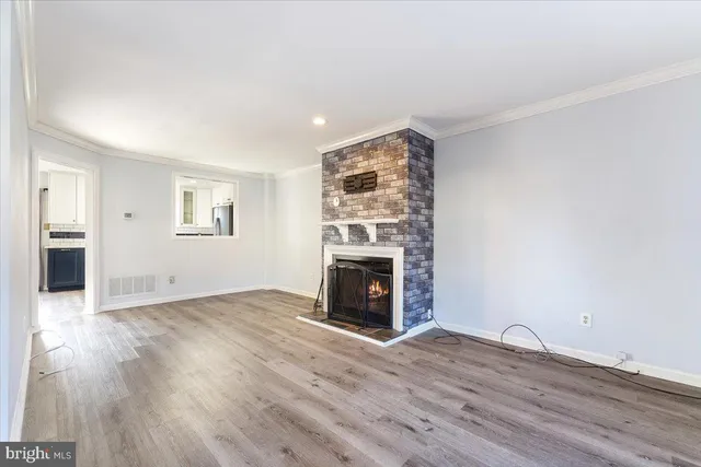 an empty room with wooden floor fireplace and windows
