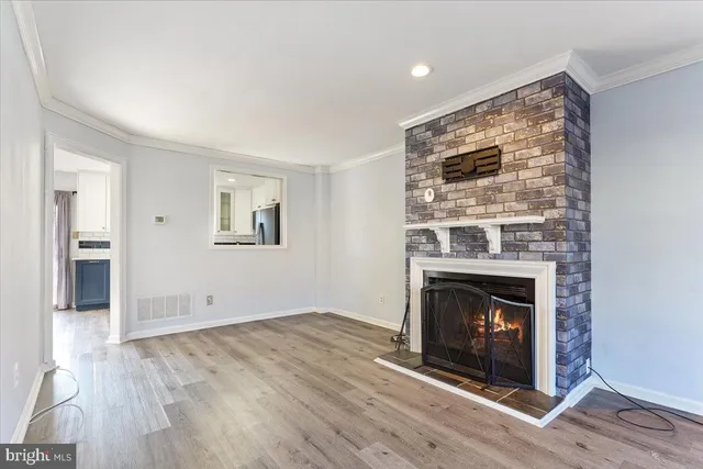a view of an empty room with wooden floor fireplace and a window