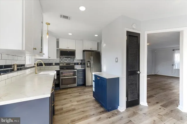 a kitchen with stainless steel appliances granite countertop a refrigerator a stove top oven a sink and dishwasher with wooden floor